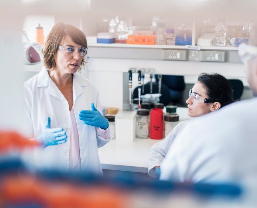 Picture of two scientists in a lab, with whtie coats & goggles