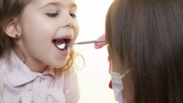 Dental professional inspecting kid mouth